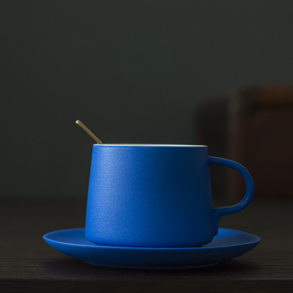 Minimalistische Porzellantasse in Kobaltblau mit Unterteller und goldenem Löffel – modernes japanisches Design für stilvollen Kaffeegenuss.