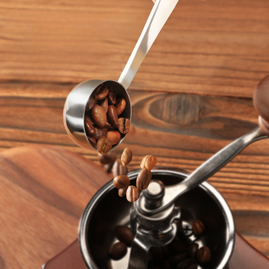 Praktischer Kaffeelöffel aus Edelstahl beim Einfüllen von Bohnen in die Mühle – präzise Dosierung leicht gemacht.