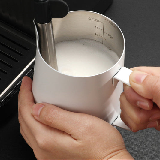 Milch wird in einem weissen Edelstahlkännchen mit Dampfdüse aufgeschäumt. Die integrierte Messskala hilft bei der präzisen Zubereitung von Milchschaum für Cappuccino oder Latte Art.