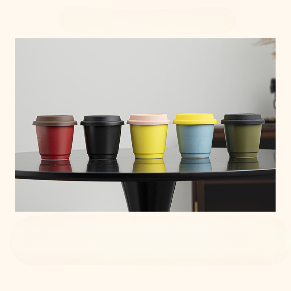 Farbige Auswahl an Mug to Go Bechern auf einem schwarzen Tisch – nachhaltige Wahl für stylische Kaffeepausen.