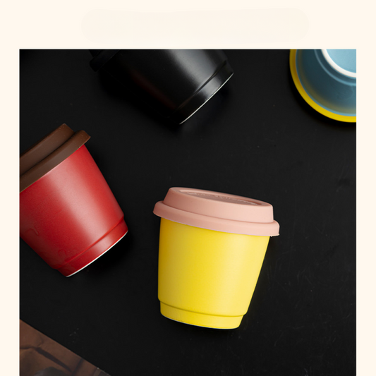 Verschiedene Mug to Go Varianten in kräftigen Farben wie Rot, Gelb und Schwarz – flach fotografiert für modernes Design-Feeling.