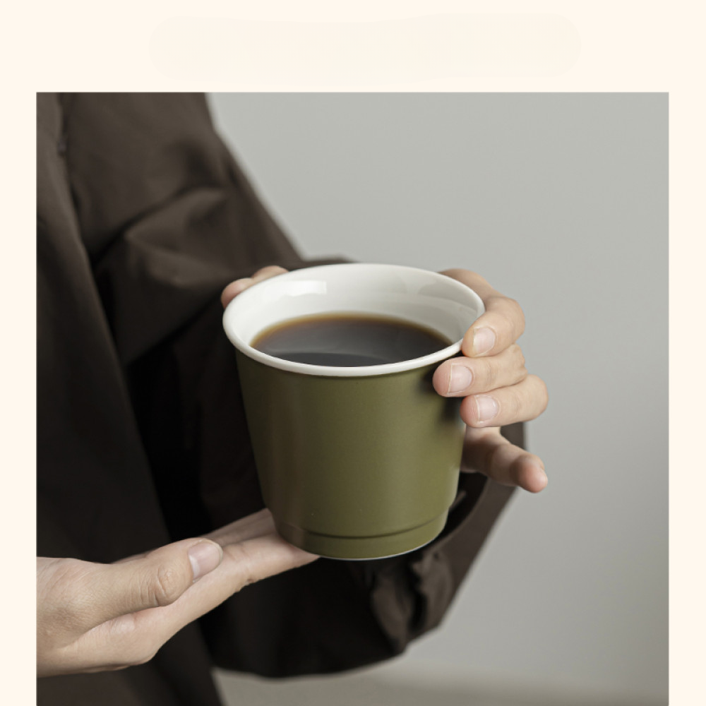 Grüner Mug to Go mit schwarzem Deckel wird in der Hand gehalten – stilvolle und praktische Lösung für unterwegs.
