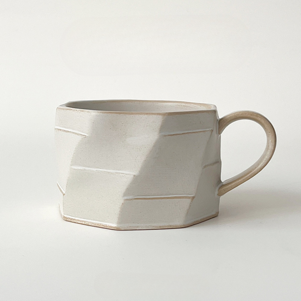 Beige Tasse mit plastischer Struktur auf hellem Hintergrund. Handgefertigtes Einzelstück in minimalistischem Look.