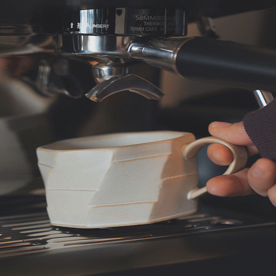 Beigefarbene Keramiktasse direkt unter dem Siebträger – im Einsatz an der Espressomaschine. Stilvoller Alltagsmoment.