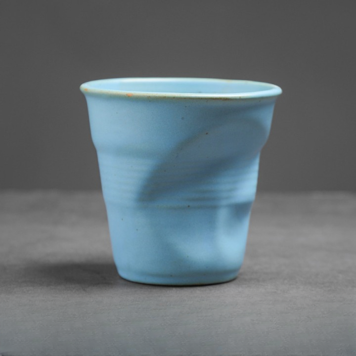 Hellblaue Keramiktasse mit natürlicher Knickstruktur. Frischer Farbton im modernen Handmade-Stil.