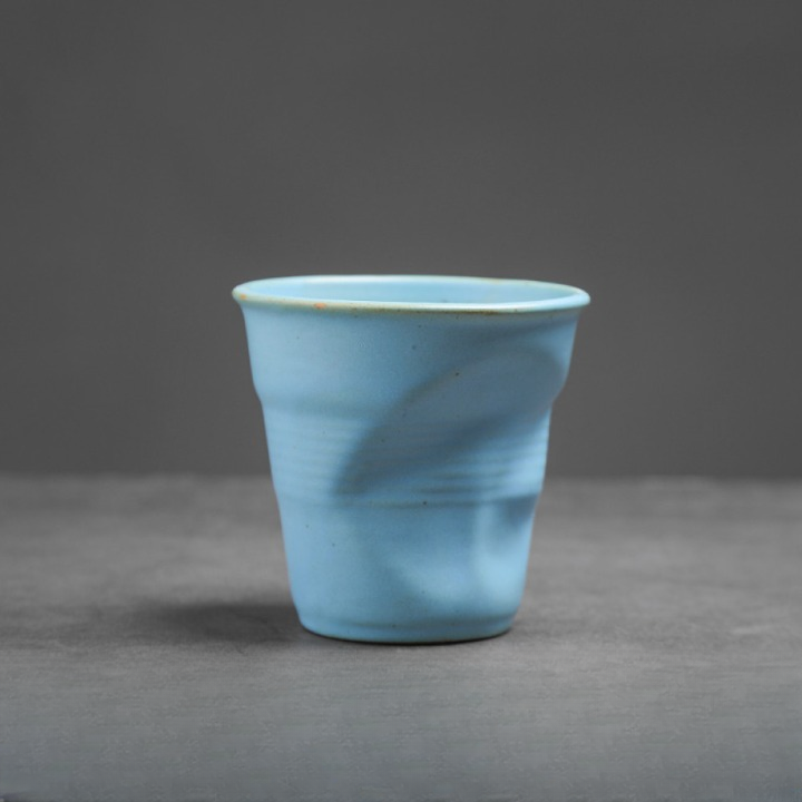 Einzelne Keramiktasse in zartem Blau mit Knickdesign. Minimalistischer Look für modernen Kaffeegenuss.