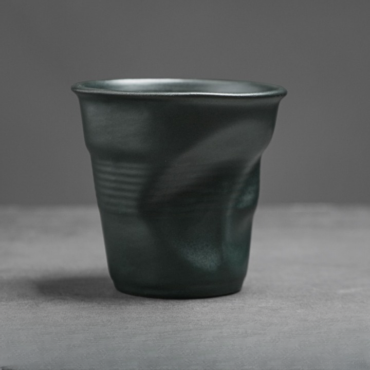 Dunkelgrüne Tasse mit matter Oberfläche und feiner Knickstruktur. Modernes Design für stilvollen Kaffeegenuss.