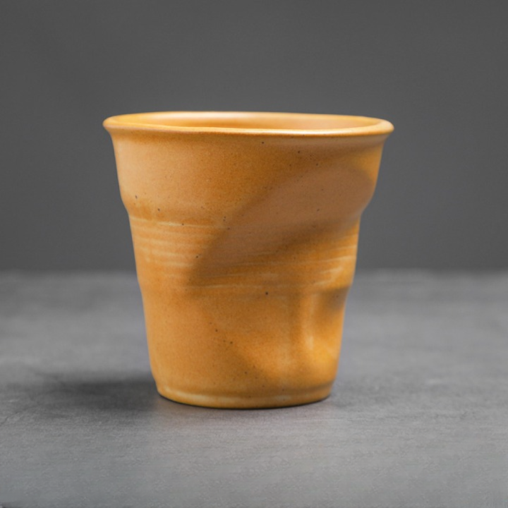 Detailaufnahme einer gelben Tasse mit Knickoptik. Ausgefallenes Design für Individualisten.