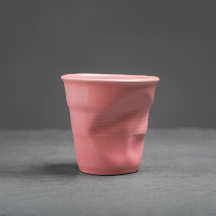 Zarte rosa Tasse mit matter Glasur und organischem Knickmuster. Sanftes Design für stilvolle Kaffeepausen.