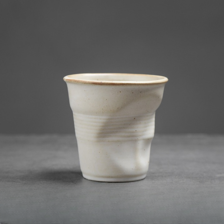 Weisse Tasse mit matter Oberfläche und Knickoptik. Ideal für modernen Tischstil mit natürlichem Touch.
