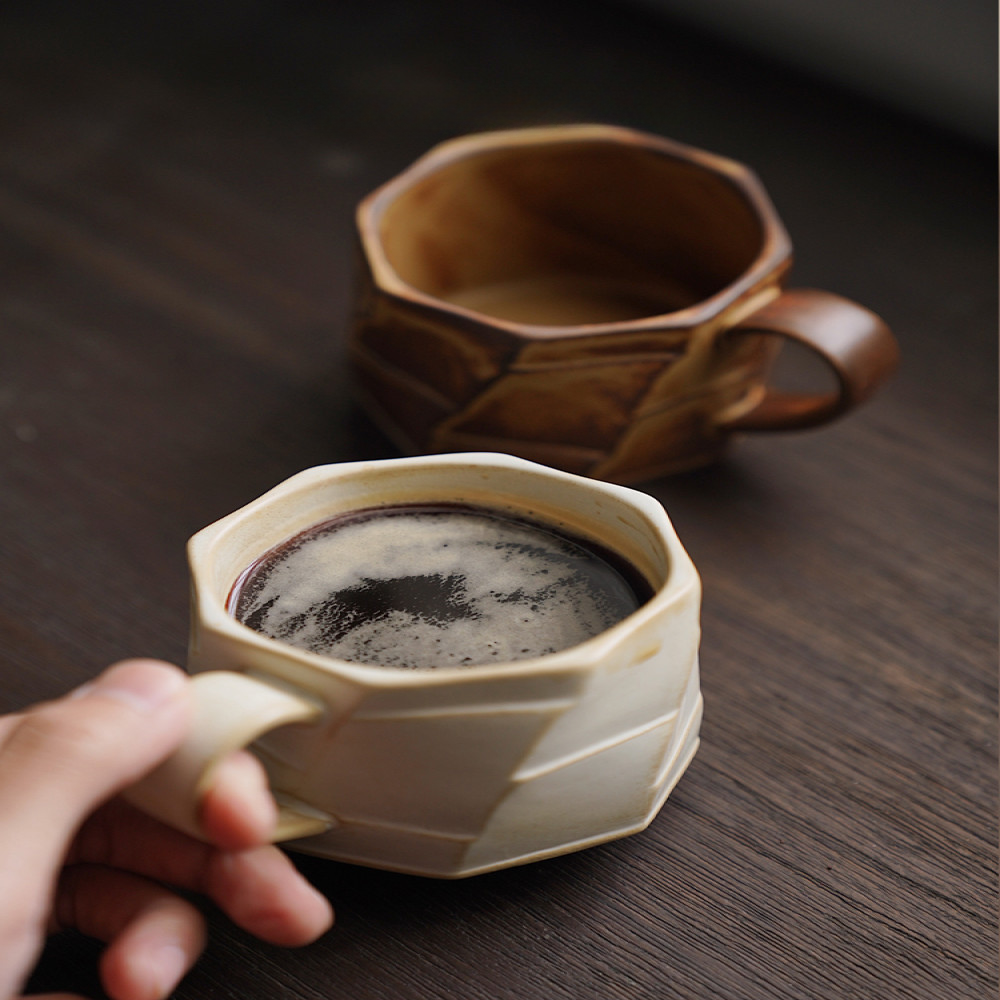 Zwei strukturierte Tassen mit frisch gebrühtem Kaffee, auf dunklem Tisch. Authentisches, modernes Design.