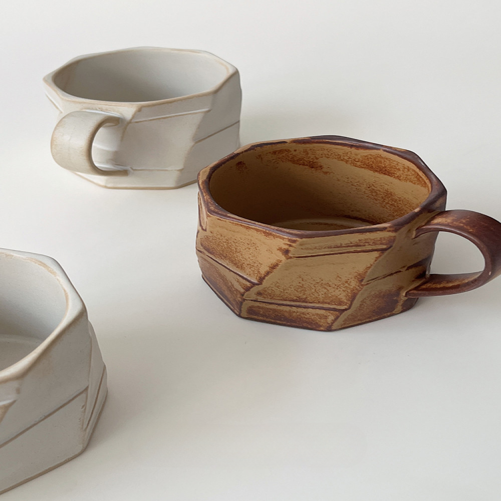 Tassen-Set in Beige und Braun nebeneinander auf weissem Hintergrund. Harmonisches Duo mit Ecken und Kanten.