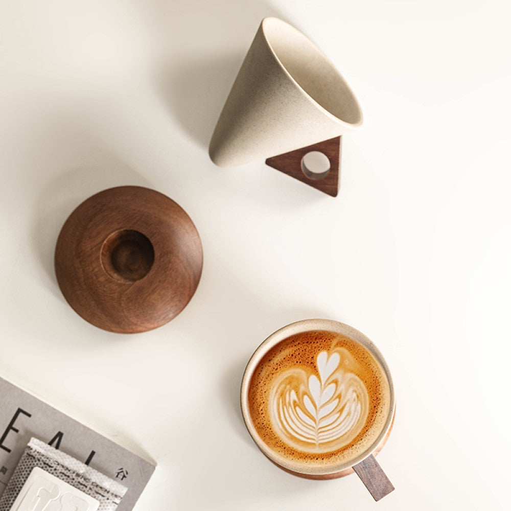 Keramiktasse, Holzunterteller und Latte Art in harmonischer Draufsicht – minimalistisch und durchdacht.