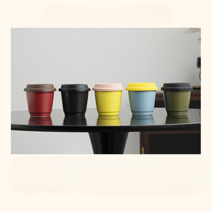 Farbige Auswahl an Mug to Go Bechern auf einem schwarzen Tisch – nachhaltige Wahl für stylische Kaffeepausen.