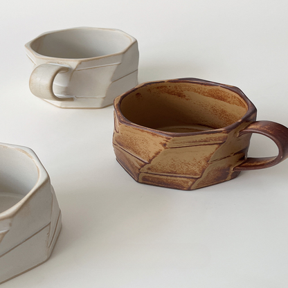Tassen-Set in Beige und Braun nebeneinander auf weissem Hintergrund. Harmonisches Duo mit Ecken und Kanten.